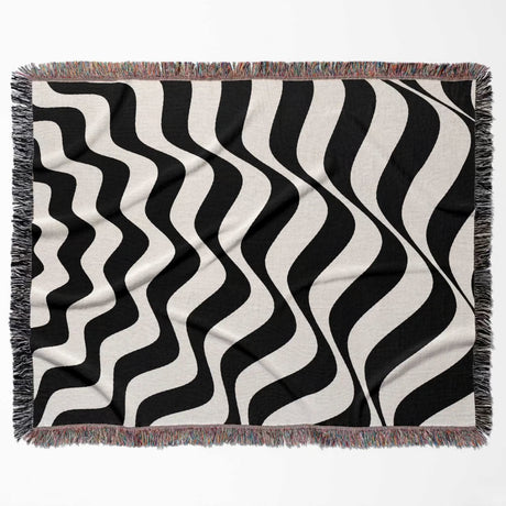 Black and white abstract wavey lines woven blanket throw tapestry flat lay on a plain background.