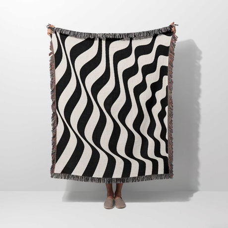 Black and white accent abstract waves woven blanket throw tapestry held by a person on a white background.