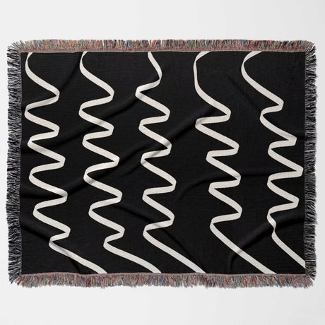 Black and white accent decorative woven blanket throw tapestry with white wavy lines flat lay on a white background