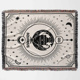 A flat, horizontal view of the Aquarius Zodiac Blanket, displaying its intricate design featuring the Aquarius symbol and celestial patterns, woven with black and off-white cotton yarns.