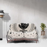 The Aquarius Zodiac Blanket spread over a couch, showcasing its large size and detailed Aquarius design. The black and off-white yarns, along with the multicolor fringe, add a stylish touch to the living room decor.