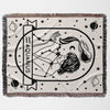 This image features a flat lay of the Aquarius Zodiac Sign Blanket. The woven throw tapestry displays a detailed black-and-white illustration of an Aquarius woman with stars and constellations. Ideal for astrology enthusiasts, it serves as both a decorative piece and a cozy blanket.