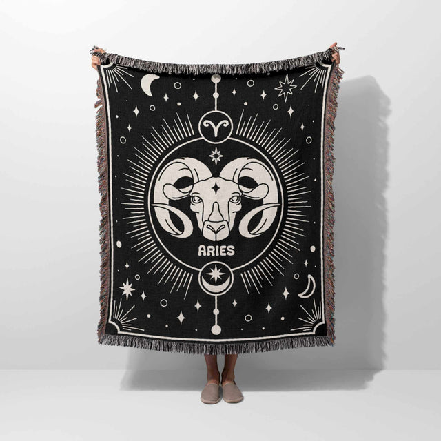 n this image, a person holds up the Aries Zodiac Blanket, giving a full view of the design. The Aries symbol is prominently displayed in the center, with zodiac patterns and multicolor fringe visible, highlighting the blanket's size and intricate details.