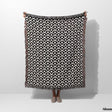 Person holding a black and white asian geometric pattern woven blanket throw tapestry with fringes on a white background