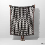 Person holding a black and white asian geometric pattern woven blanket throw tapestry with fringes on a white background