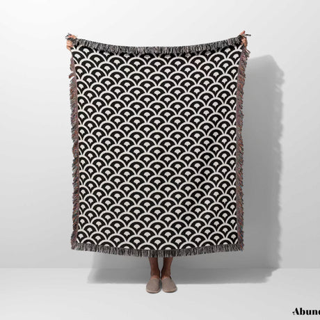 Person holding a black and white asian geometric pattern woven blanket throw tapestry with fringes on a white background