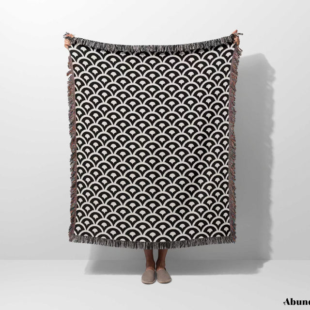 Person holding a black and white asian geometric pattern woven blanket throw tapestry with fringes on a white background