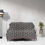 Black and white asian geometric pattern woven blanket throw tapestry on a sofa against a white wall.