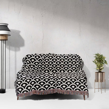 Black and white asian geometric pattern woven blanket throw tapestry on a sofa against a white wall.