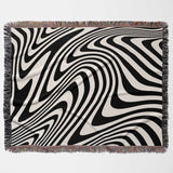 black and white modern couch woven throw blanket with fringed edges on a light gray background