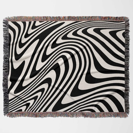 black and white modern couch woven throw blanket with fringed edges on a light gray background
