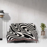 Black and white modern couch woven throw blanket on a sofa against a white wall.