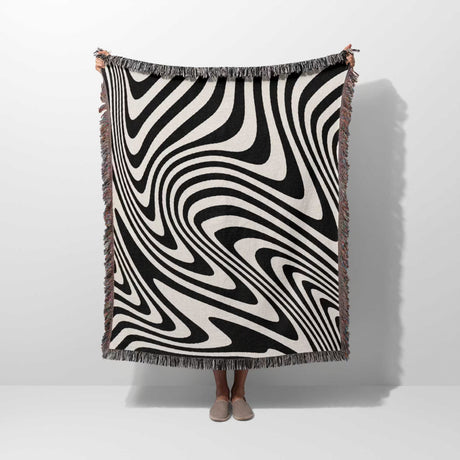 Person holding a black and white modern couch woven throw blanket against a white background