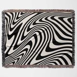 Black and white modern decorative woven throw blanket with fringed edges on a white background
