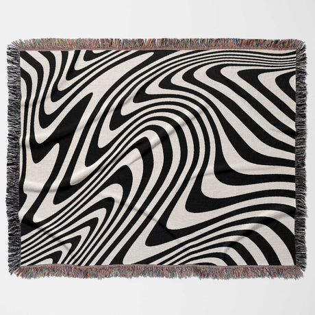 Black and white modern decorative woven throw blanket with fringed edges on a white background