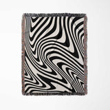 Black and white modern decorative woven throw blanket with fringes on a light gray background
