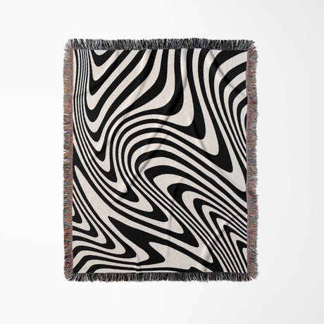 Black and white modern decorative woven throw blanket with fringes on a light gray background