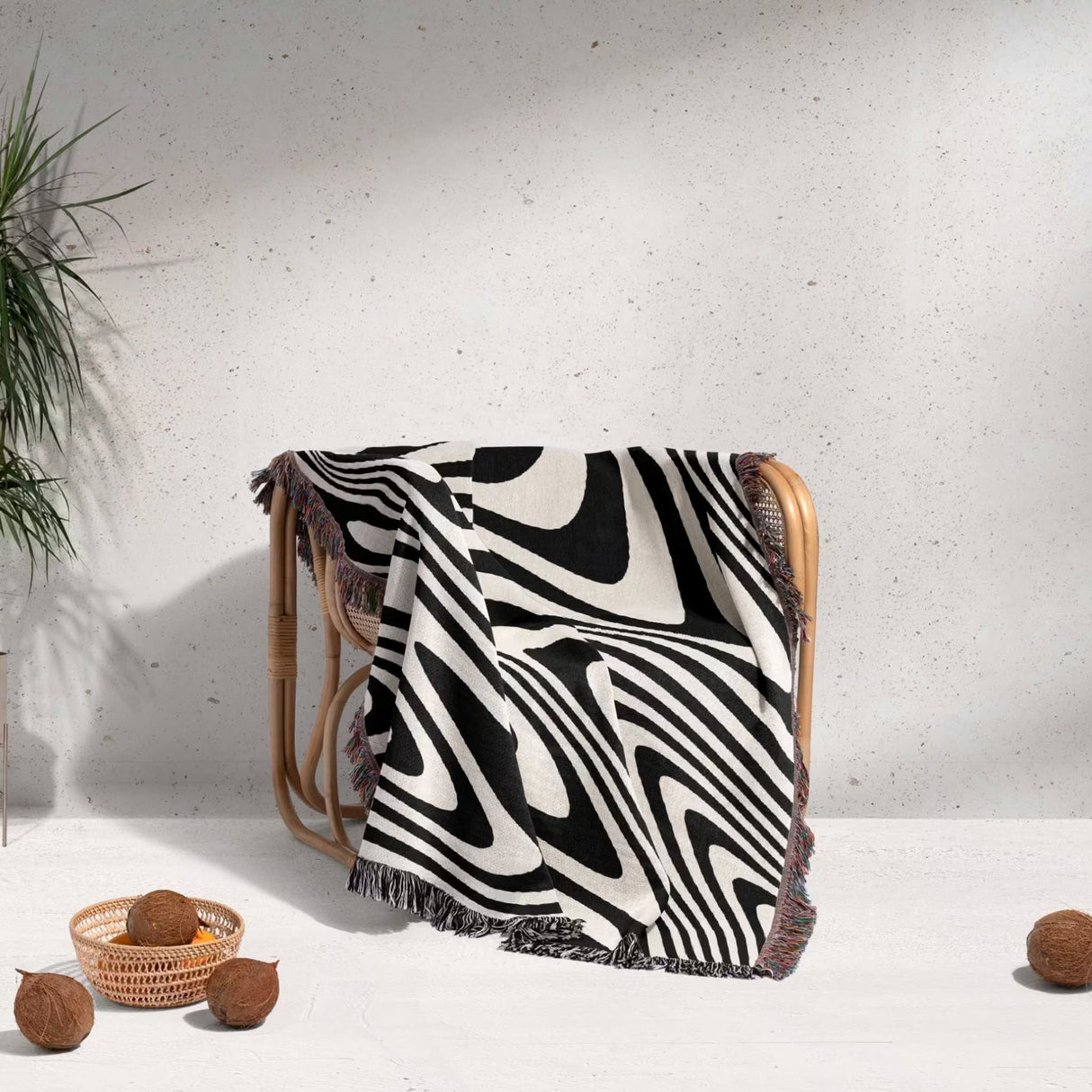 black and white modern decorative woven throw blanket draped over a chair on a light gray background