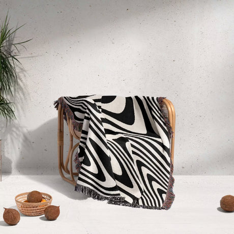 black and white modern decorative woven throw blanket draped over a chair on a light gray background