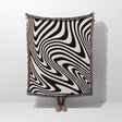 Person holding a black and white modern decorative woven throw blanket against a white background