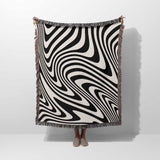 Person holding a black and white modern decorative woven throw blanket against a white background