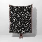 Black blanket with white abstract patterns draped over a person on a white background