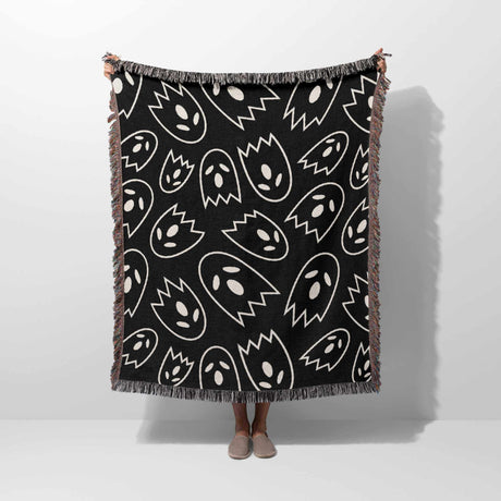 Black blanket with white abstract patterns draped over a person on a white background