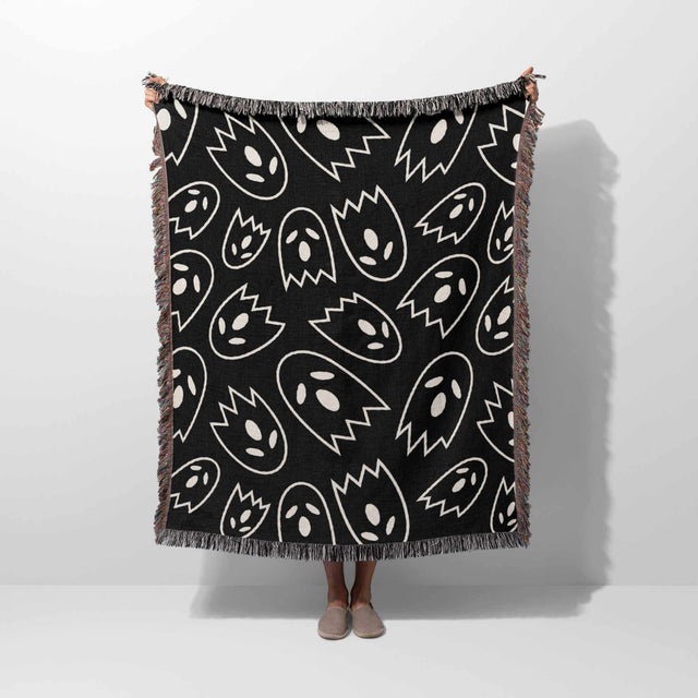 Black blanket with white abstract patterns draped over a person on a white background