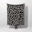 Person holding a black blanket with white pattern against a white background