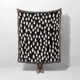 Person holding a black blanket with white pattern against a white background