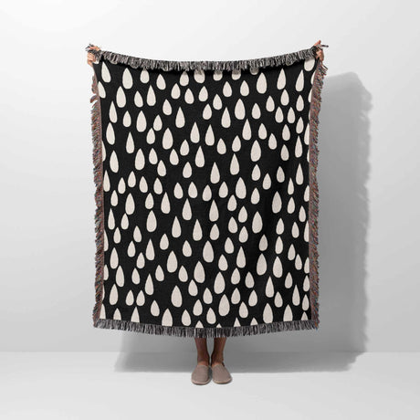 Person holding a black blanket with white pattern against a white background