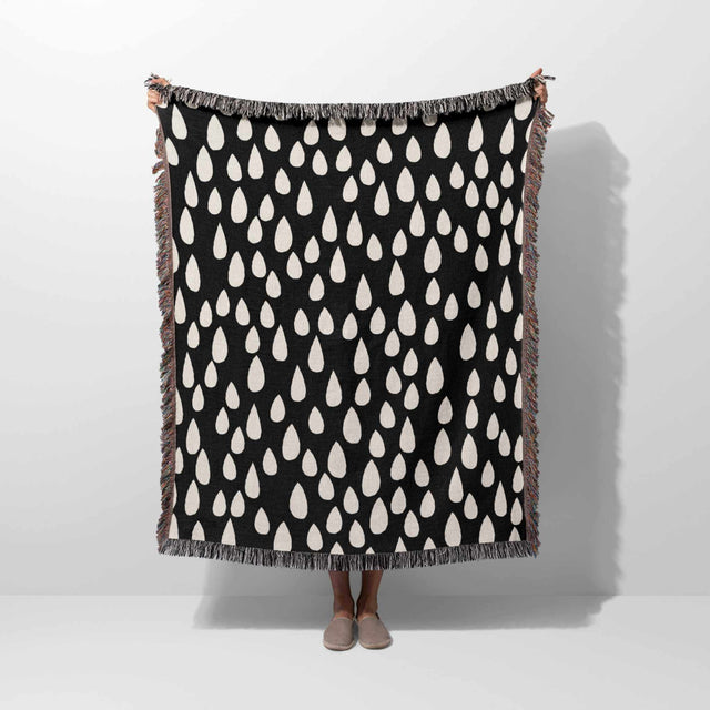 Person holding a black blanket with white pattern against a white background