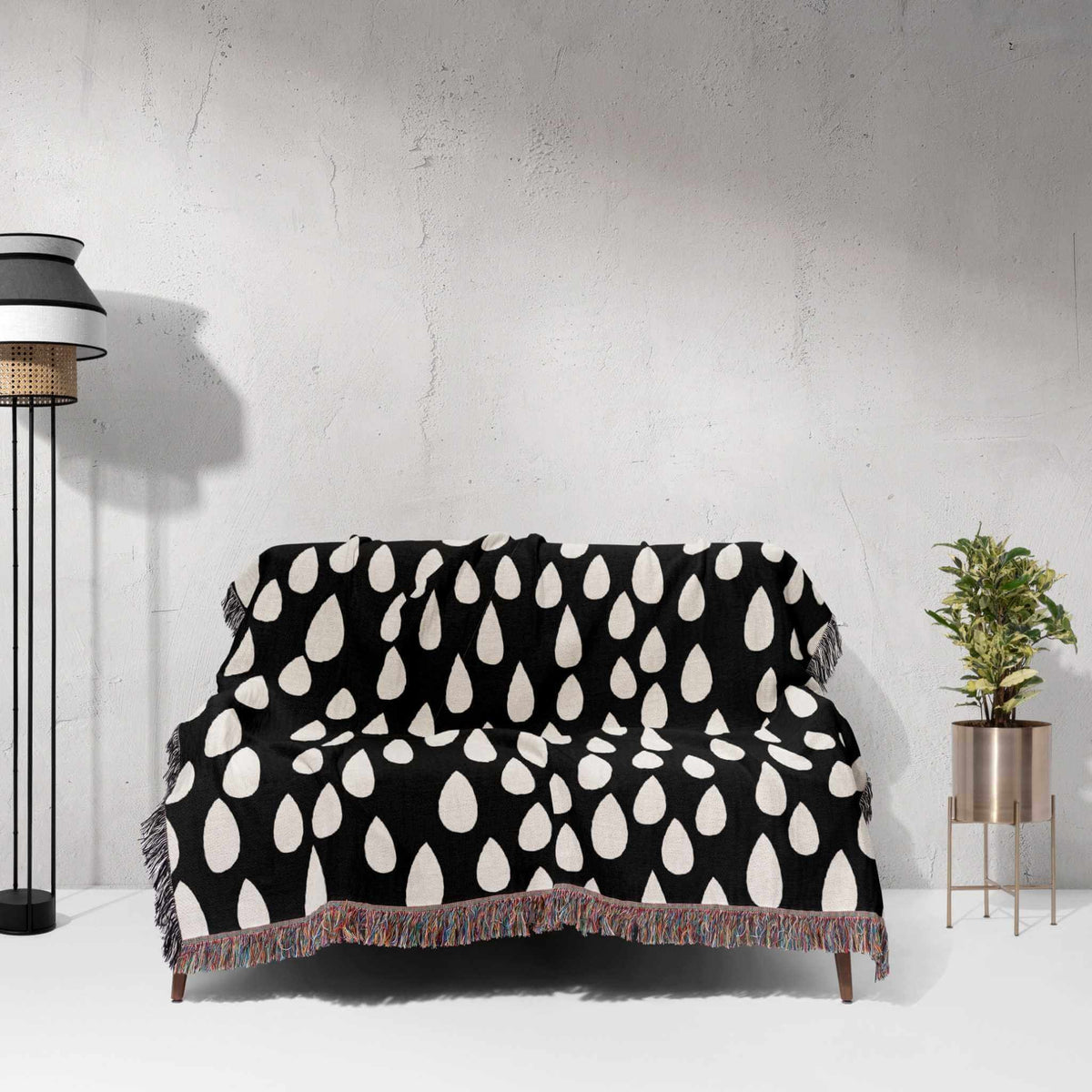 Black and white patterned blanket draped over a sofa against a light gray wall.