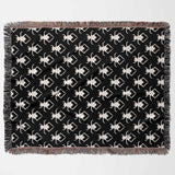 Black and white geometric spiders pattern woven throw blanket flat lay on a white background.