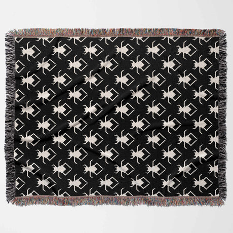 Black and white geometric spiders pattern woven throw blanket flat lay on a white background.