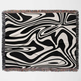 Black and white marble woven throw blanket for couch with fringed edges on a light gray background