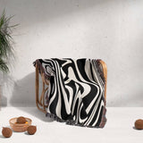 Black and white marble woven throw blanket for couch draped over a wooden chair against a light gray wall.