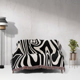 Black and white marble woven throw blanket for couch draped over a couch against a light gray wall.