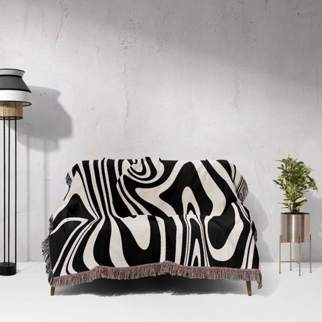 Black and white marble woven throw blanket for couch draped over a couch against a light gray wall.