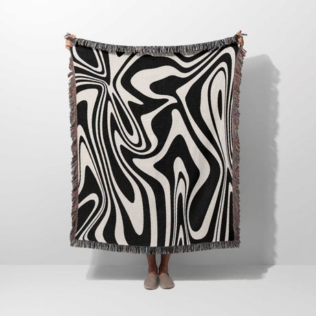 Abstract black and white marble woven throw blanket for couch on a person against a white background