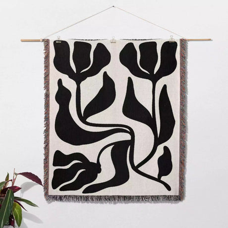 Black and white Matisse flower woven throw blanket and woven tapestry with black floral patterns on a white background
