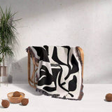 Black and white Matisse flower woven throw blanket patterned draped over a chair against a light gray wall.