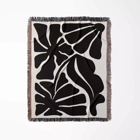 Black and white abstract patterned with black and white Matisse flowers woven throw blanket on a white background
