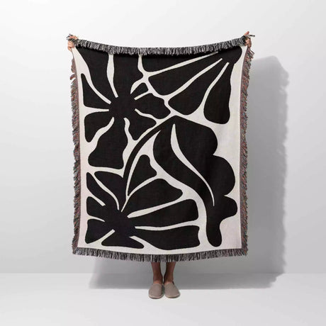 Black and white Matisse flowers woven throw blanket floral patterned blanket held by a person on a white background