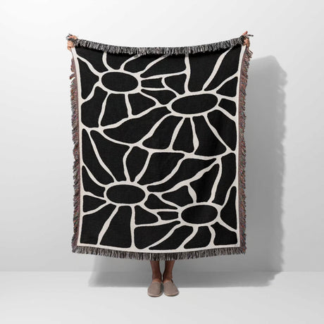 Person holding a black and white Matisse tapestry throw blanket for couch against a white background