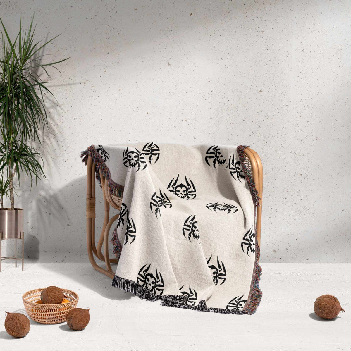 White blanket with black patterns draped over a wooden chair against a light gray wall.