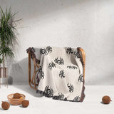 White blanket with black patterns draped over a wooden chair against a light gray wall.