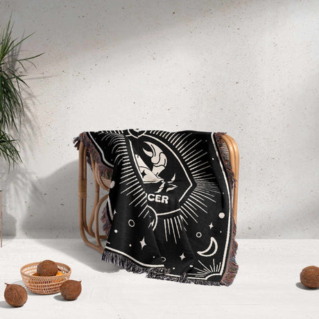 The Cancer Zodiac Blanket is artistically draped over a chair, demonstrating its decorative and functional use. The blanket adds a cozy and stylish touch to any room, perfect for home decor enthusiasts.