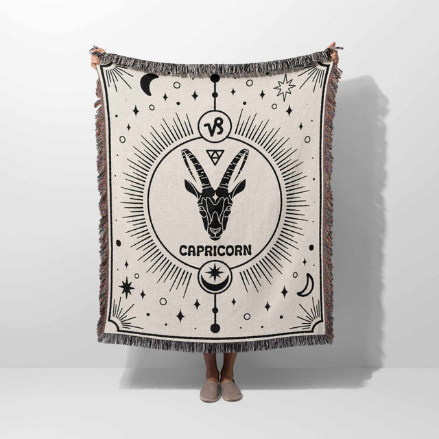 A person holding the Capricorn Zodiac Blanket vertically, showing the full extent of its intricate design. This unique woven throw is an excellent birthday gift for women and men, blending practicality with a personalized astrological touch.