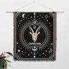 The Capricorn Zodiac Blanket hanging on a wall as decor, showcasing its detailed design with the Capricorn symbol in the center, surrounded by stars and celestial elements. The multicolored fringe adds a vibrant border to the piece.